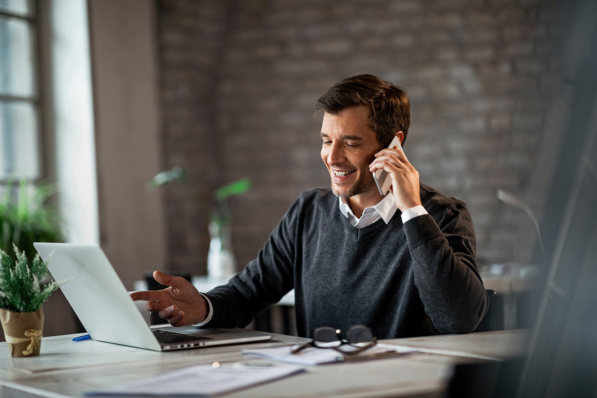 a smiling businessman on the phone at his computer